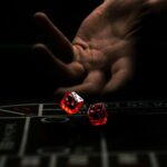 a hand with a finger pointing at a red and white dice
