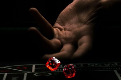a hand with a finger pointing at a red and white dice